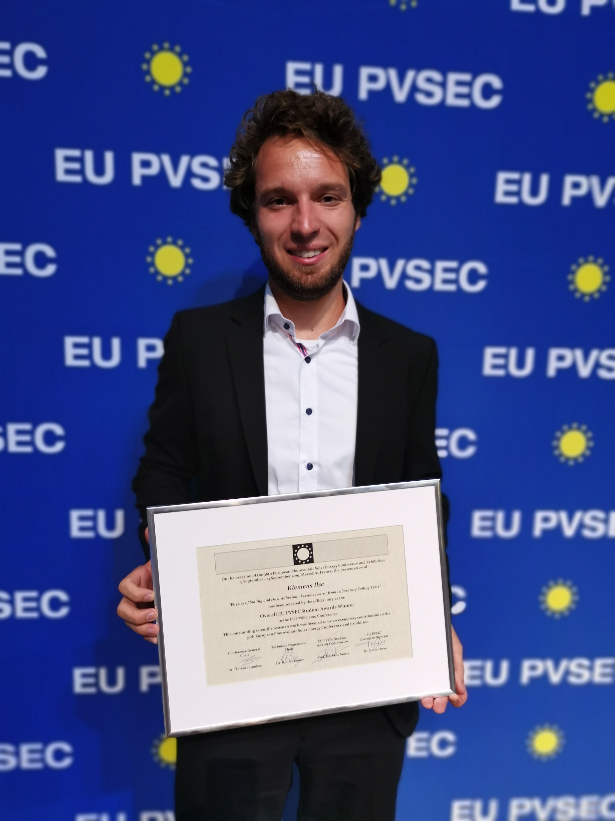 Forscher Klemens Ilse vor Leindwand mit Auszeichnung der Photovoltaik-Konferenz